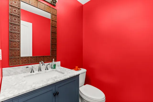a bathroom with a granite countertop toilet sink and mirror