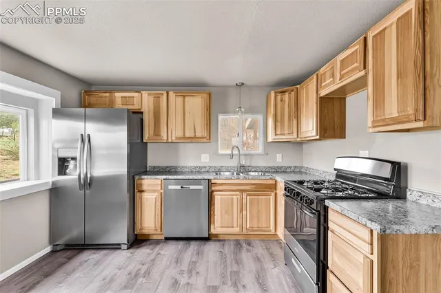 a kitchen with granite countertop a refrigerator stove top oven and sink