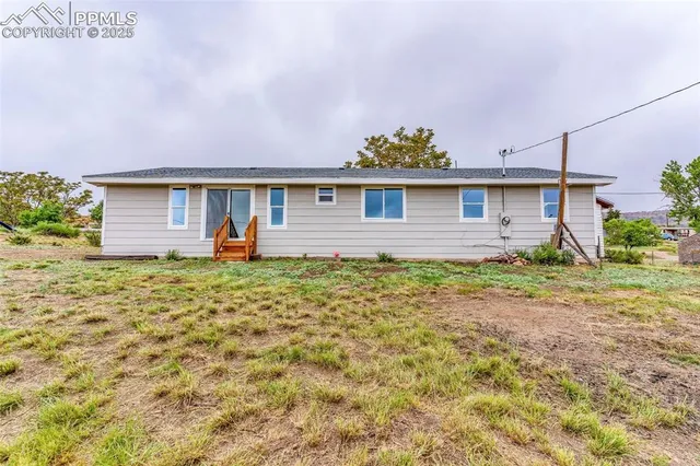 a front view of house with yard and trees in the background
