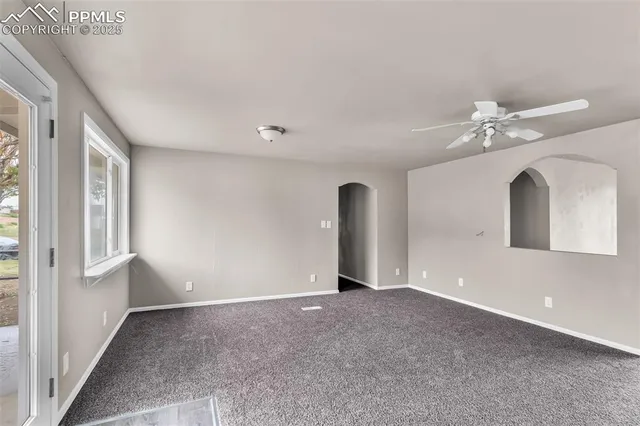 a view of a big room with windows and chandelier fan