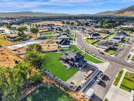1327 West 500 North Mapleton, UT 84664 - Photo 10 of 54 Aerial view of a contemporary residential community featuring a dark-toned property with a manicured lawn, established trees, and surrounding concrete hardscaping