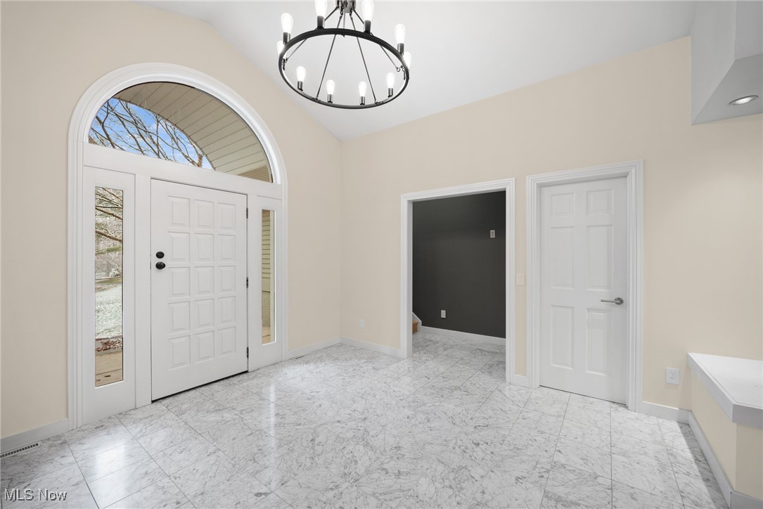 2711 Glenmont Road Northwest Canton, OH 44708 - Photo 11 of 42 Foyer entrance with lofted ceiling, a chandelier, healthy amount of natural light, and marble look tiles