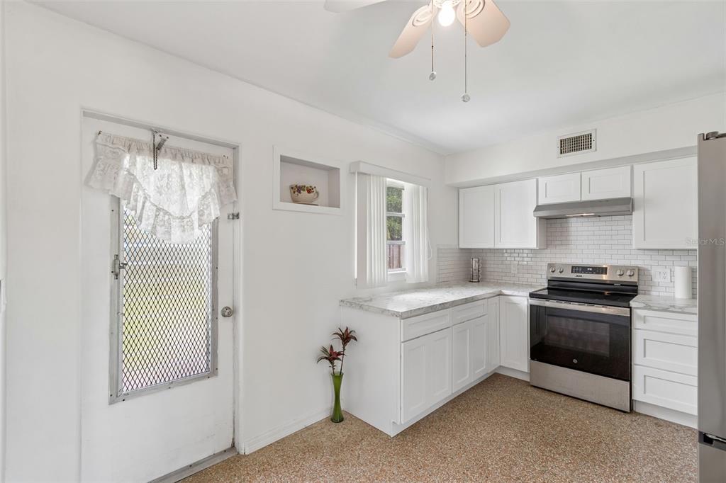 6634 Manor Beach Road New Port Richey, FL 34652 - Photo 15 of 64 a kitchen with stainless steel appliances white cabinets and a chandelier