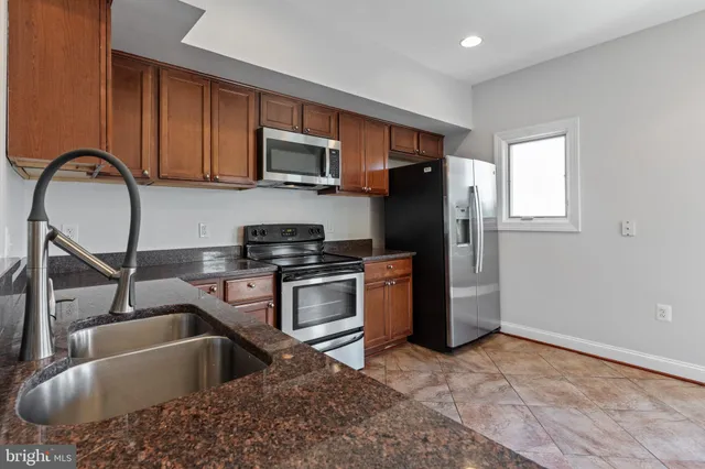 a kitchen with stainless steel appliances granite countertop a refrigerator sink and stove