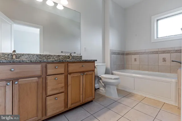 a bathroom with a granite countertop toilet a sink and a bathtub