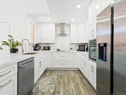 a kitchen with granite countertop white cabinets and stainless steel appliances
