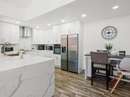 a kitchen with stainless steel appliances granite countertop a refrigerator a stove and a dining table with wooden floor