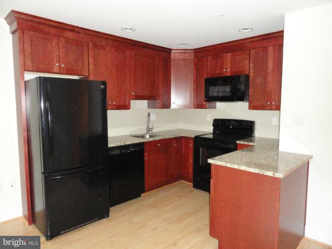 1237 Kenyon Street Northwest, Unit A Washington, DC 20010 - Photo 2 of 6 a kitchen with a refrigerator sink and cabinets