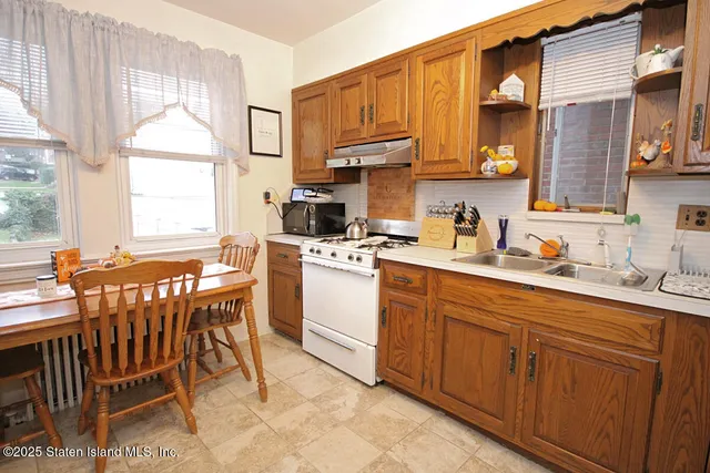 a kitchen with a sink a window and chairs