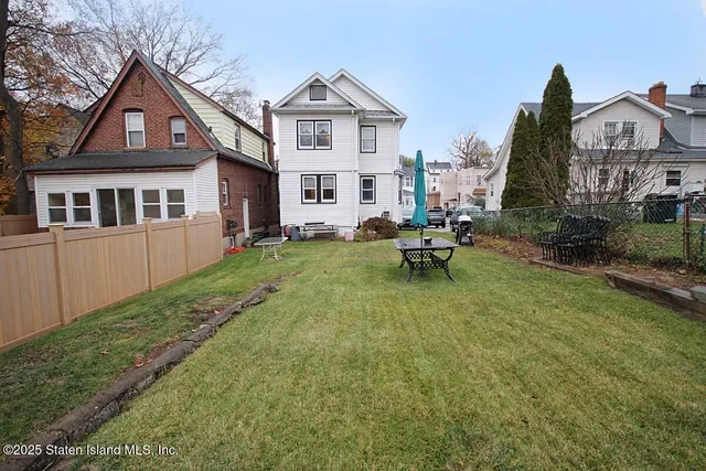 a view of a brick house with a yard and large trees