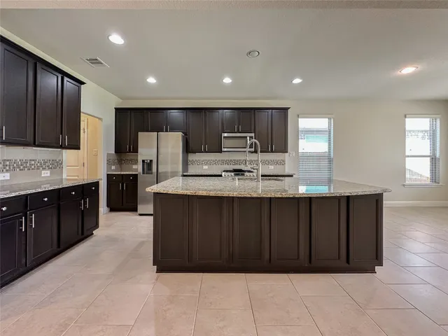 a large kitchen with kitchen island granite countertop wooden cabinets a sink and dishwasher