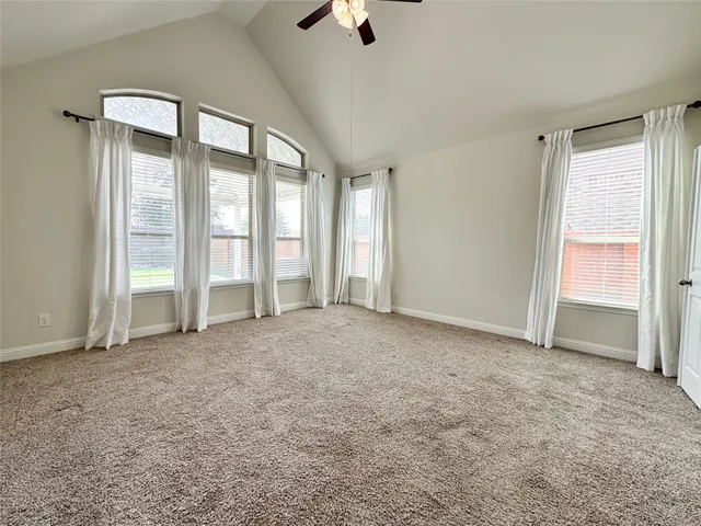 an empty room with chandelier fan and windows
