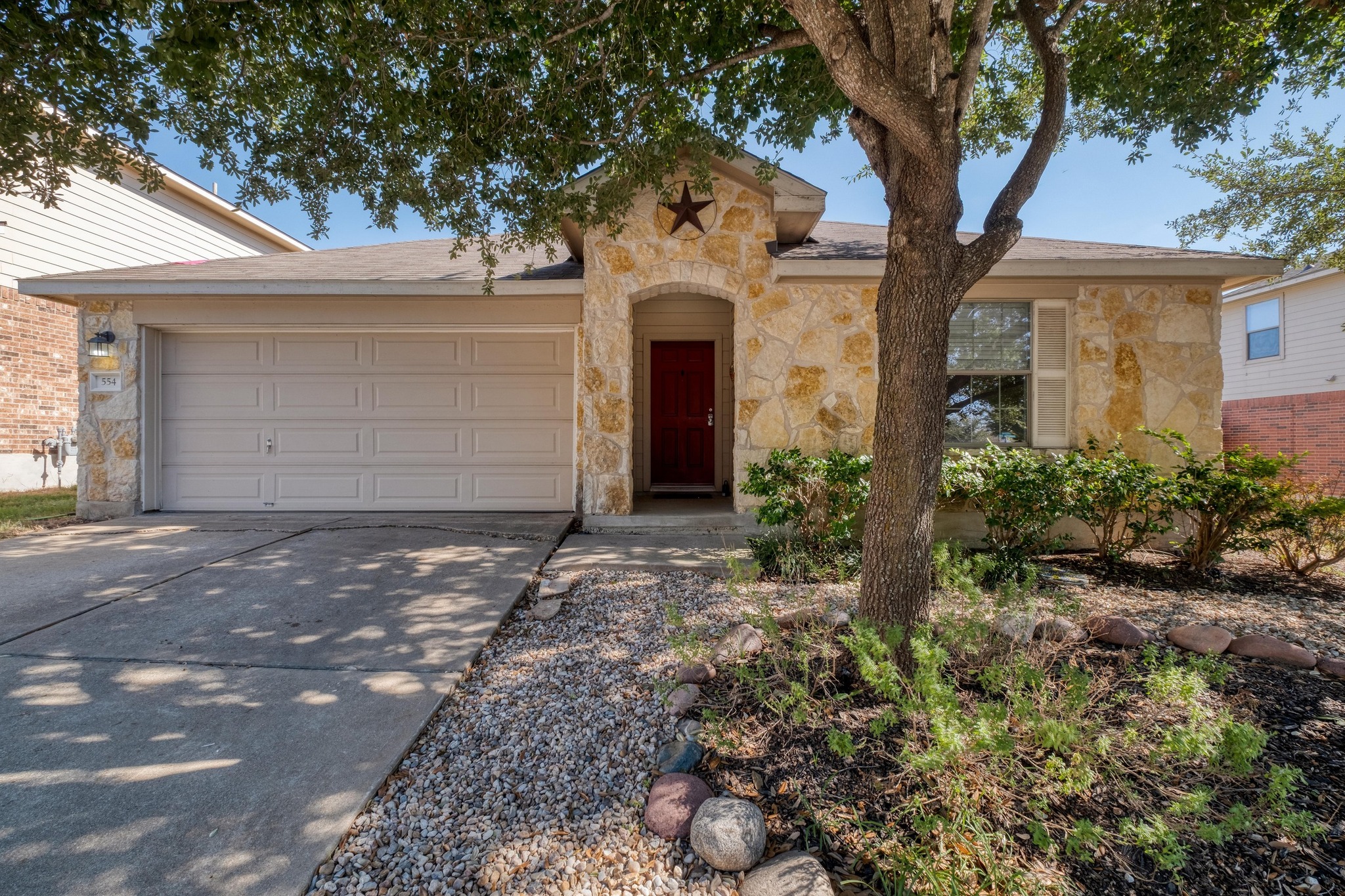 554 Sandstone Trail Buda, TX 78610 - Photo 1 of 1 A well-kept exterior framed by a mature tree and a mix of native landscaping creates a polished, welcoming first impression
