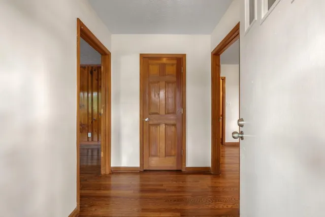a view of an empty room with wooden floor and a bathroom