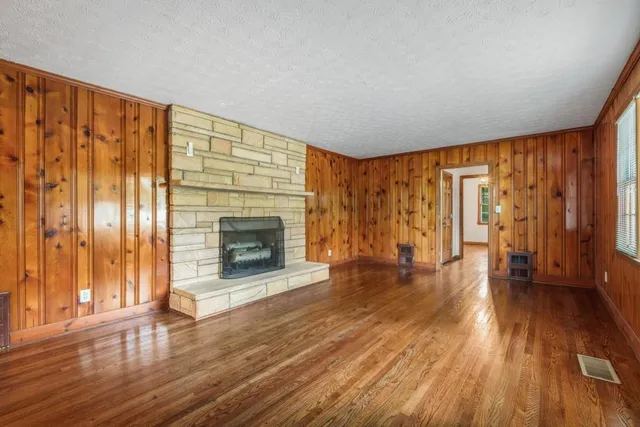 a view of an empty room with wooden floor and a fireplace
