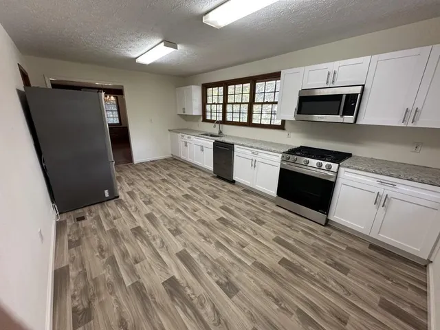 a kitchen with granite countertop a refrigerator stove and sink
