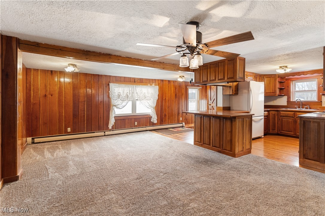 5070 Russell Road Andover, OH 44003 - Photo 14 of 25 Kitchen with kitchen peninsula, white refrigerator, a healthy amount of sunlight, and a baseboard heating unit