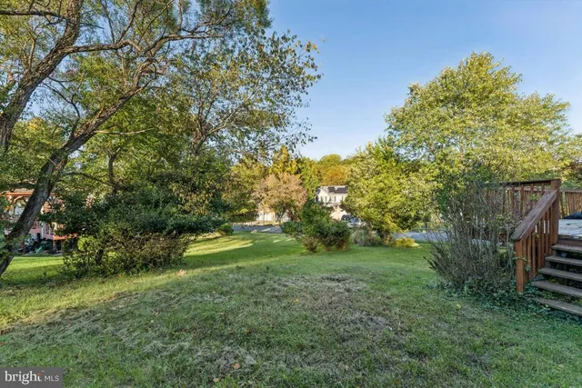 a view of a house next to a big yard and large trees