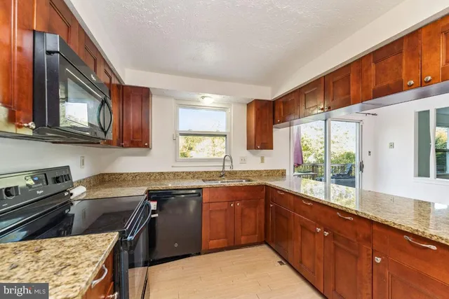 a kitchen with granite countertop wooden cabinets a stove top oven and stainless steel appliances