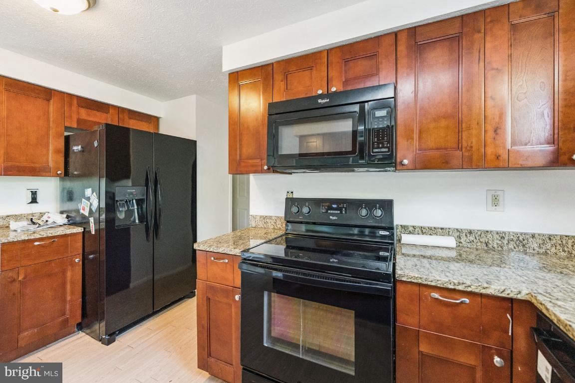 8106 Triple Crown Road Bowie, MD 20715 - Photo 10 of 26 a kitchen with granite countertop wooden cabinets a stove top oven and stainless steel appliances