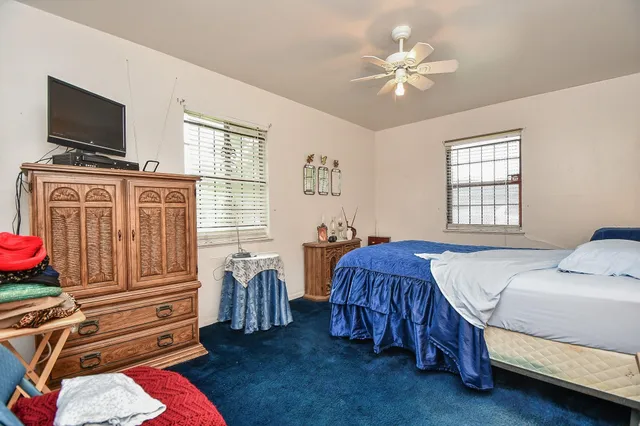 a bedroom with a bed next to a window with the dresser