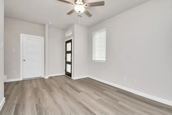 an empty room with wooden floor fan and windows