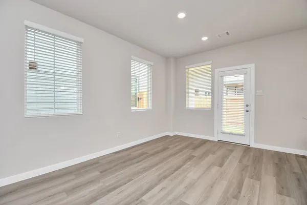 an empty room with wooden floor and windows