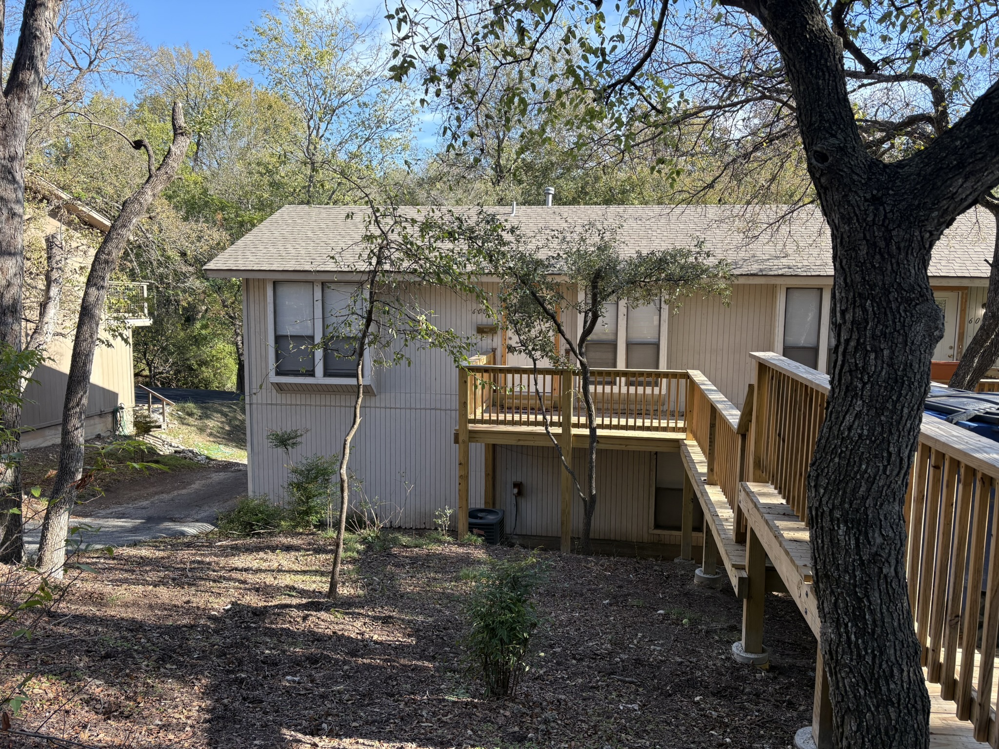 Rear view of house featuring stairway, a deck, and roof with shingles