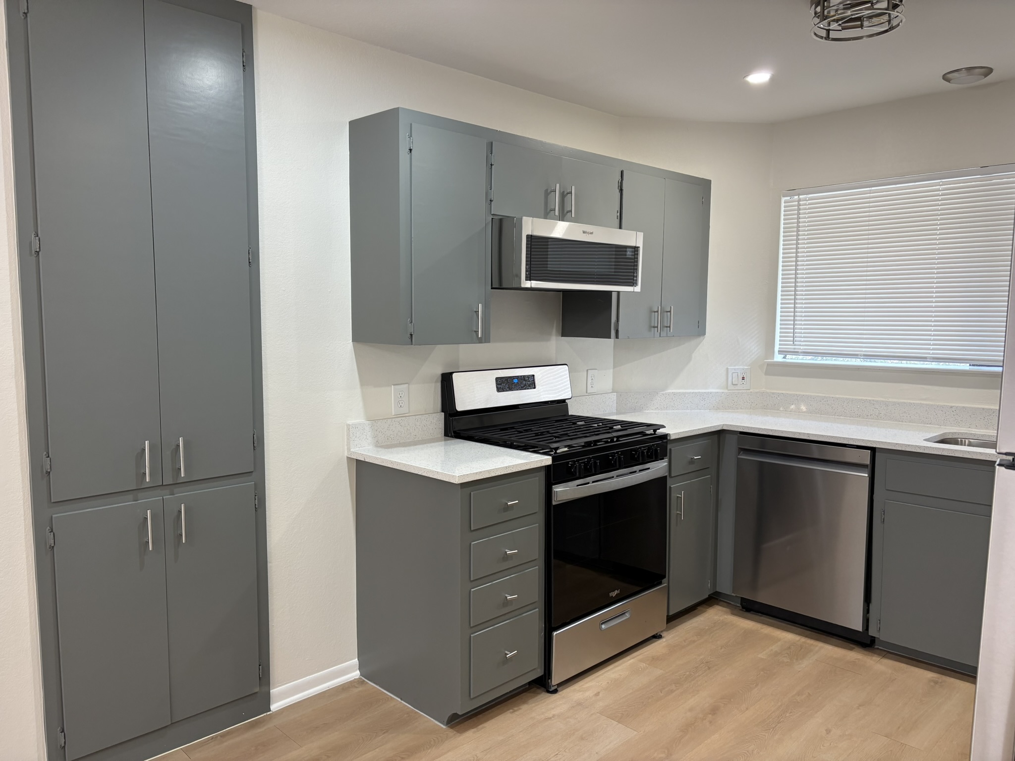 6009 Shadow Valley Cove, Unit A Austin, TX 78731 - Photo 8 of 24 Kitchen with gray cabinets, appliances with stainless steel finishes, light wood-type flooring, light stone counters, and recessed lighting