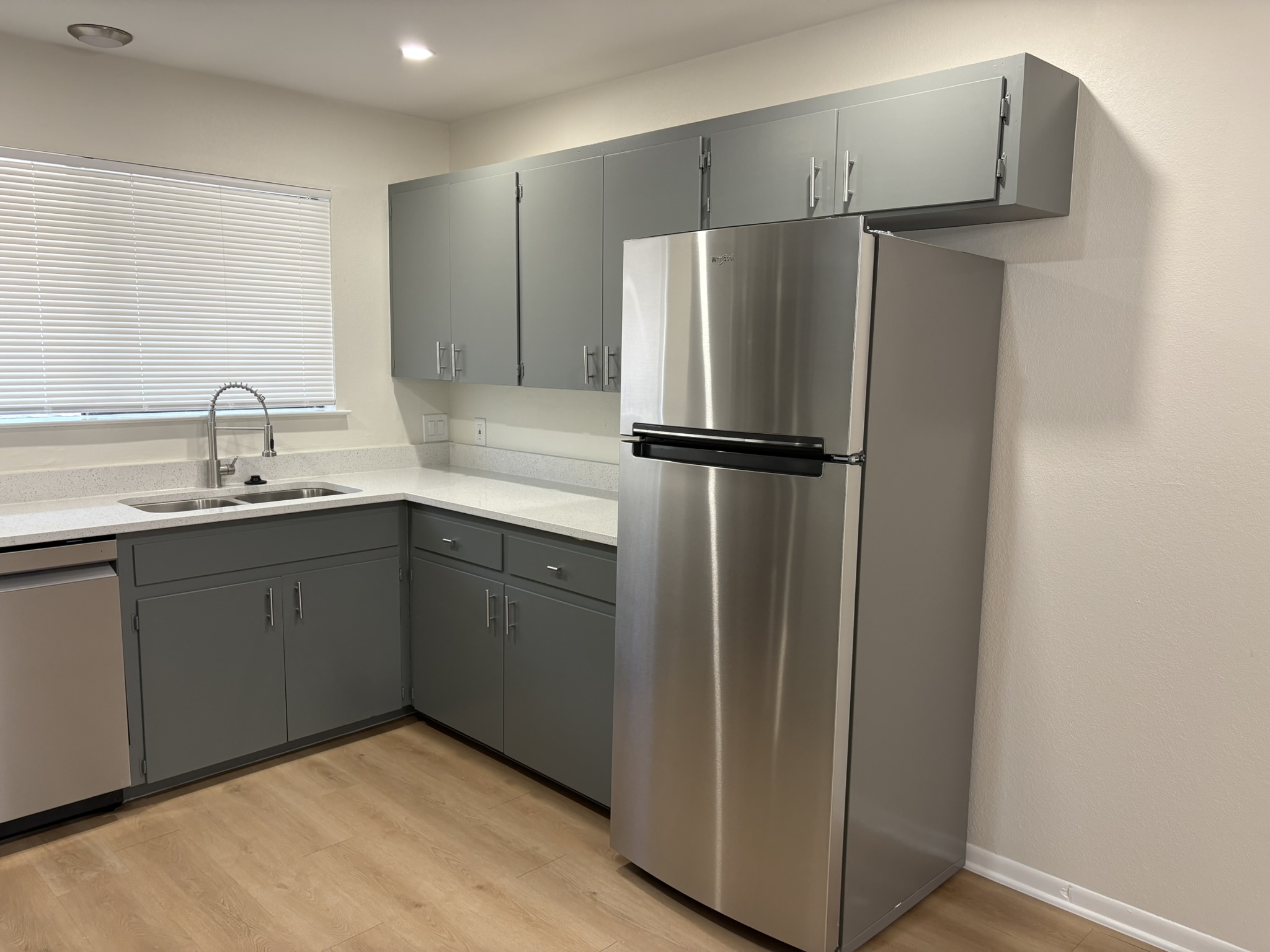6009 Shadow Valley Cove, Unit A Austin, TX 78731 - Photo 9 of 24 Kitchen featuring gray cabinetry, stainless steel appliances, light wood-style flooring, and light stone countertops