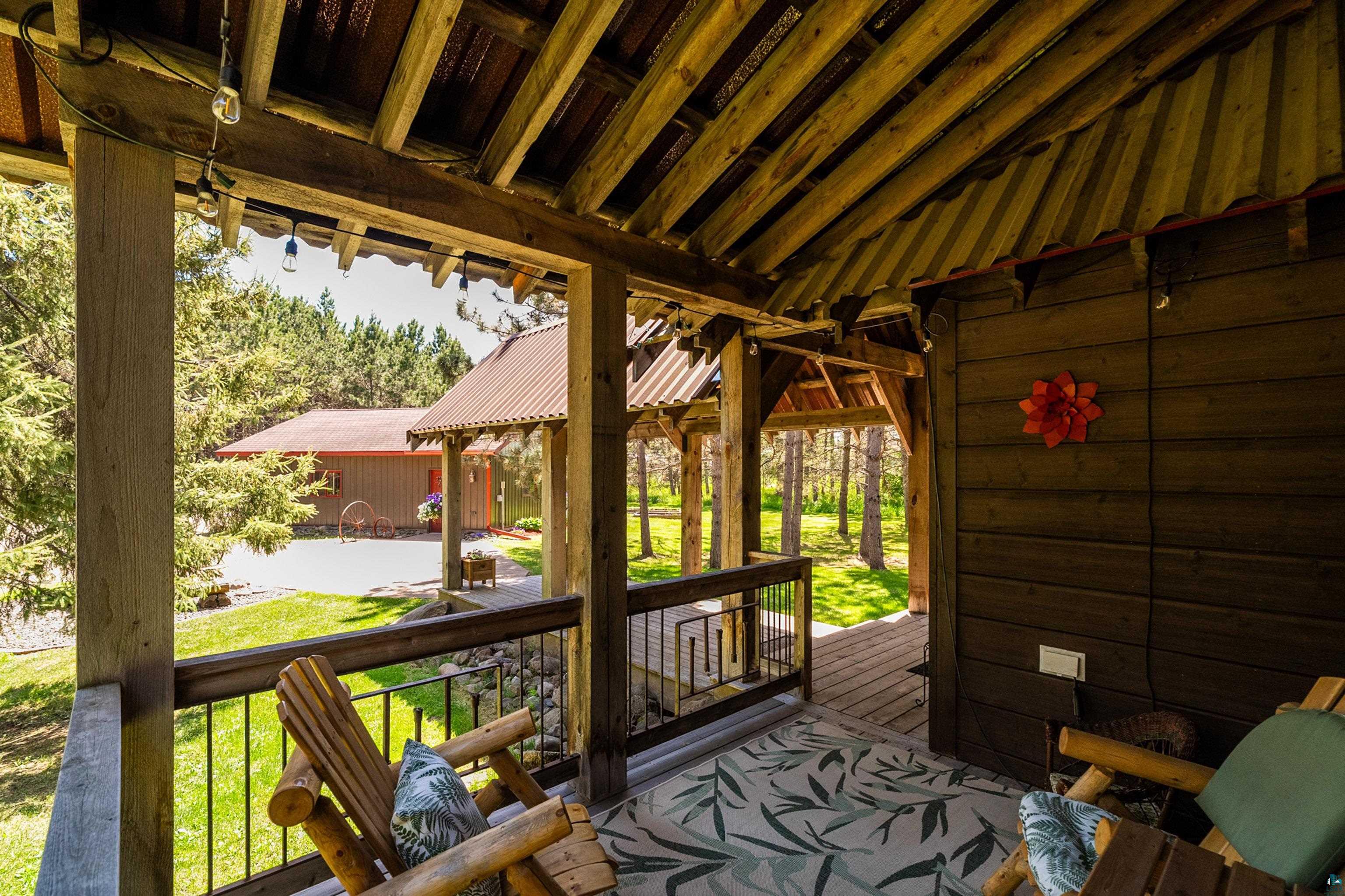 75 East Stark Road Esko, MN 55733 - Photo 7 of 87 Covered porch featuring exposed wood beams, wood paneling, and an outdoor area rug