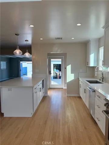 a large kitchen with stainless steel appliances a large counter top a sink a stove and a wooden floors