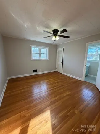 a view of empty room with wooden floor and fan