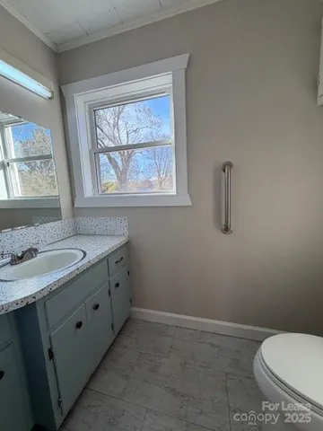 a bathroom with a granite countertop sink toilet and mirror