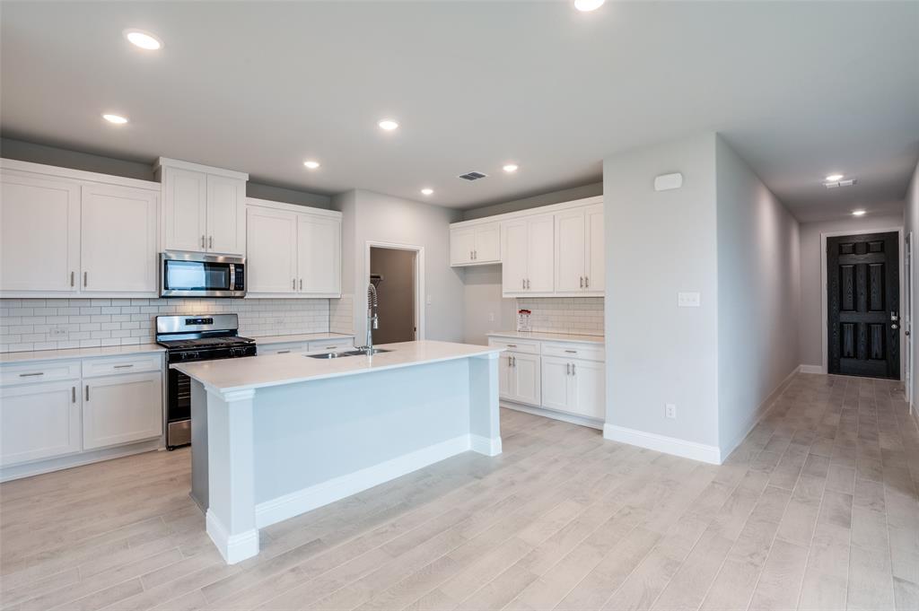 832 Santa Lucia Drive Anna, TX 75409 - Photo 4 of 33 Kitchen featuring tasteful backsplash, appliances with stainless steel finishes, white cabinetry, a kitchen island with sink, and recessed lighting