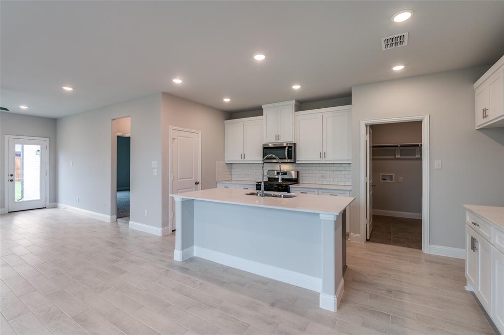 832 Santa Lucia Drive Anna, TX 75409 - Photo 6 of 33 Kitchen featuring white cabinetry, tasteful backsplash, recessed lighting, a center island with sink, and appliances with stainless steel finishes