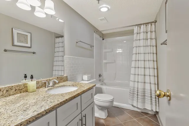 a bathroom with a granite countertop sink a toilet and shower