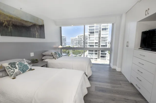 a bedroom with two large bed and a flat tv screen on dresser