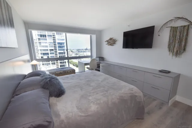 a large bedroom with a bed and flat tv screen on the dresser