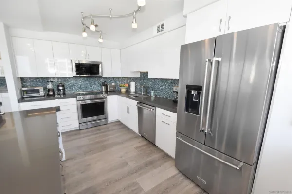 a kitchen with stainless steel appliances granite countertop a refrigerator a stove a sink a microwave and white cabinets