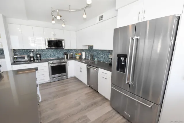 a kitchen with stainless steel appliances granite countertop a refrigerator a stove a sink a microwave and white cabinets