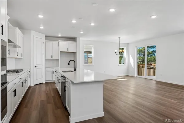 a kitchen with granite countertop a stove a sink a refrigerator and cabinets