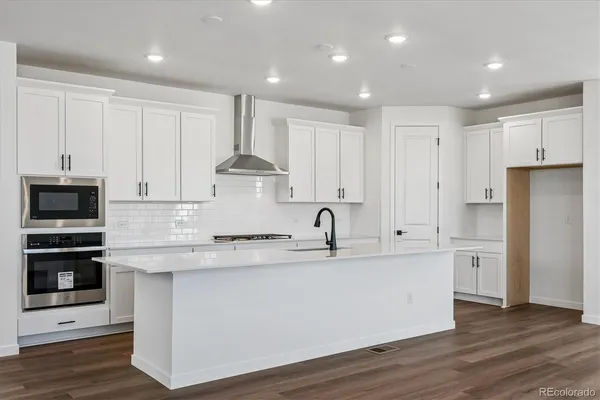 a large kitchen with stainless steel appliances granite countertop a stove a sink and a refrigerator