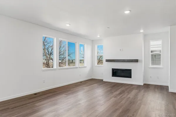 an empty room with windows and fireplace
