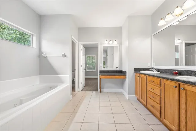 a bathroom with a tub a sink and a large mirror