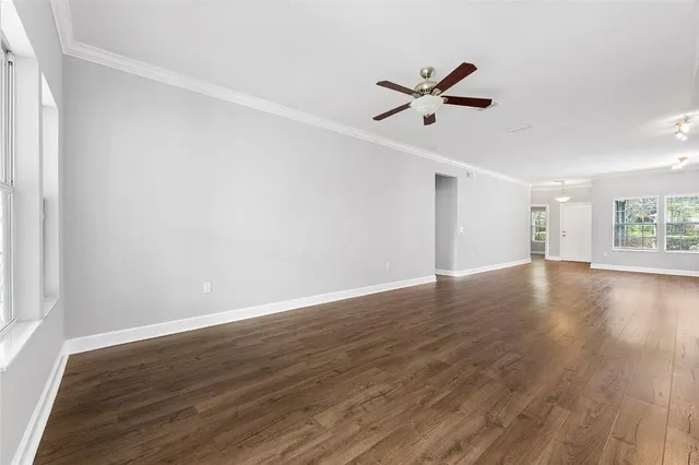 a view of empty room with wooden floor and fan