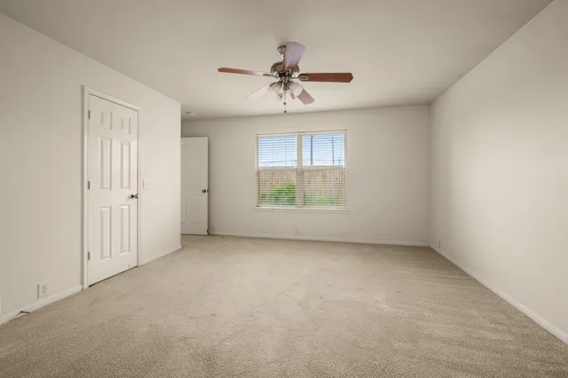 an empty room with a window and a ceiling fan