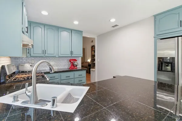 a kitchen with granite countertop a sink cabinets and stainless steel appliances