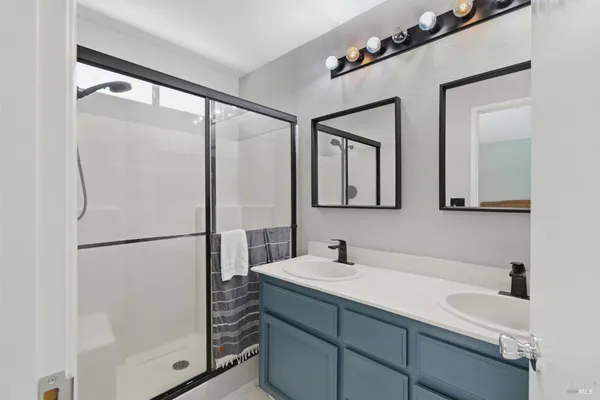 a bathroom with a double vanity sink mirror and shower
