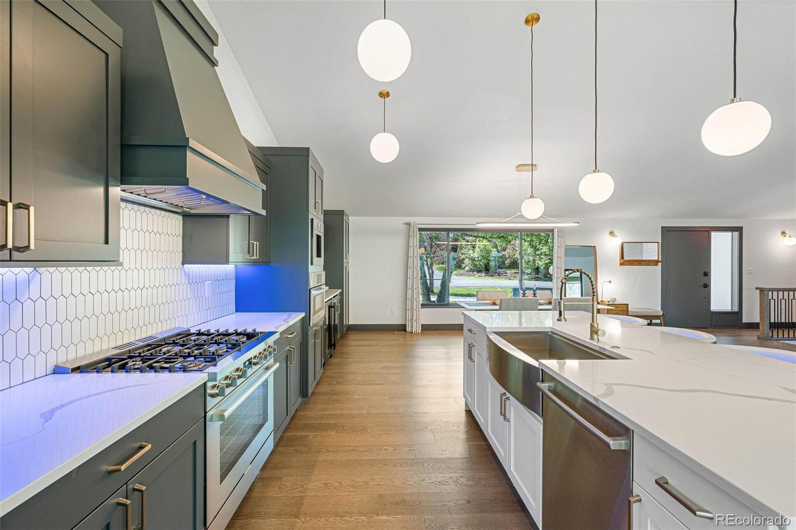 17 Rangeview Drive Wheat Ridge, CO 80215 - Photo 14 of 50 a kitchen with stainless steel appliances kitchen island a large stove a sink dishwasher and white cabinets with wooden floor